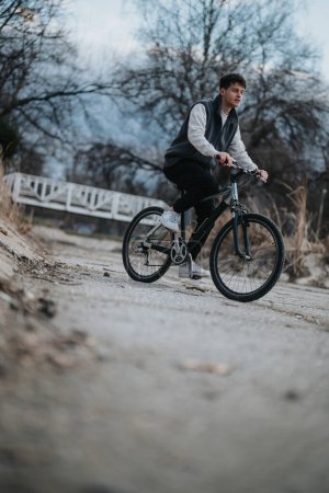 A young male teenager is captured mid-ride on his bicycle along a park trail, conveying a sense of freedom and leisure.