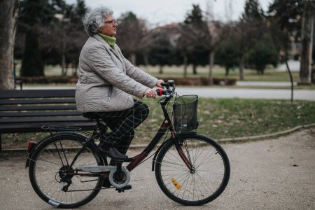 Mature woman enjoying her retirement with a leisurely bicycle ride in a serene park setting.
