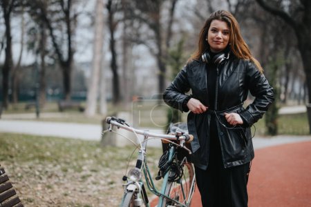 Confident businesswoman with her bicycle taking a leisurely break in an urban park, showcasing a healthy work-life balance.