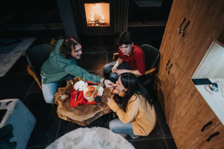 A top view of friends gathered around a rustic table enjoying a meal together in a comfortable home with a fireplace.