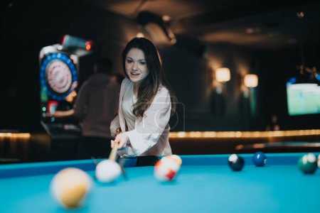Smiling female player having fun playing billiards with her companions, holding pool cue ready for the game