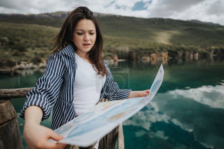 Junge Reisende konsultiert eine Landkarte, während sie landschaftlich reizvolle Naturumgebungen erkundet, die Freizeit und Abenteuer verkörpern.