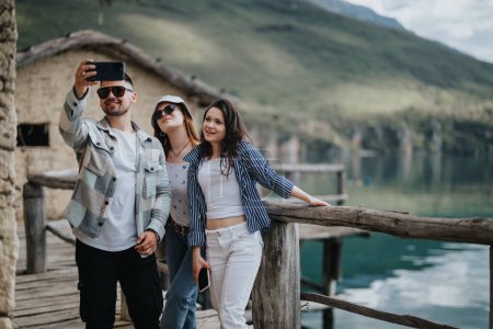 Junge Reisende halten einen Moment zusammen mit einem Selfie auf einem Holzsteg mit Blick auf einen ruhigen Bergsee fest.