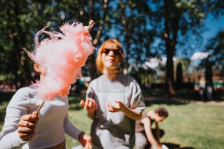 Un grupo de amigos disfrutan de un día soleado al aire libre, compartiendo dulces de algodón y buenos momentos en un parque de la ciudad, encarnando alegría y unión..