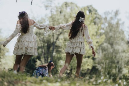 Three sisters run playfully through a lush park, hands linked, dressed in flowy dresses on a sunny, spring day. Feelings of freedom and togetherness exude.