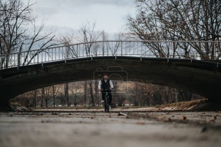 Male teenager relishes leisure time cycling in nature, depicting freedom and joy under a bridge.