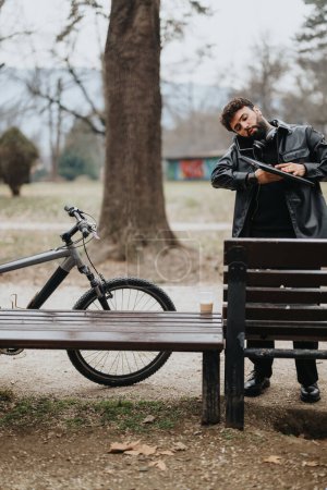Homme d'affaires concentré en tenue élégante travaille à distance sur une tablette, à côté de son vélo dans un cadre de parc urbain serein.