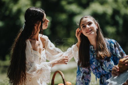 Two sisters sharing a joyful moment outdoors, enjoying a sunny day at the park while having a picnic together.