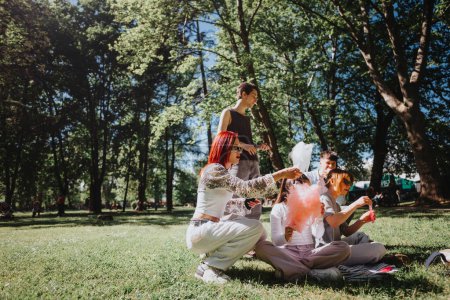 Un grupo de amigos sentados en la hierba de un parque, compartiendo dulces de algodón rosa en un día alegre y soleado, rodeados de árboles y disfrutando de la compañía de los demás.