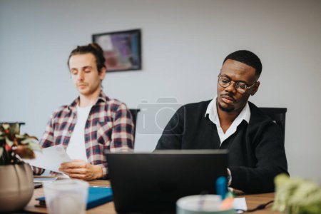 Two male colleagues concentrate on work in an office setting, discussing ideas and strategies for project growth and success.
