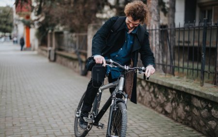 A professional businessman with curly hair dismounting his bicycle in a casual urban setting, conveying eco-friendly commuting.