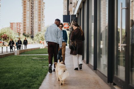 Three professionals casually discussing business while walking dogs on a city sidewalk, showcasing a relaxed work atmosphere.
