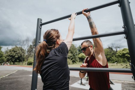 A man and a woman engage in a strenuous workout at outdoor gym equipment under a clear sky, showcasing teamwork and health.