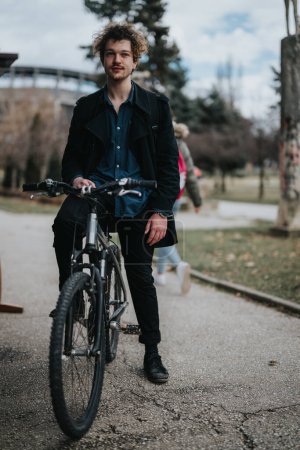 Young professional male with curly hair standing with his bike, showcasing an active lifestyle and eco-friendly commuting.