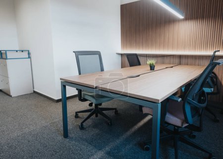 A contemporary meeting room featuring a large wooden table, comfortable chairs, and decorative lighting. Ideal for business discussions and team meetings.