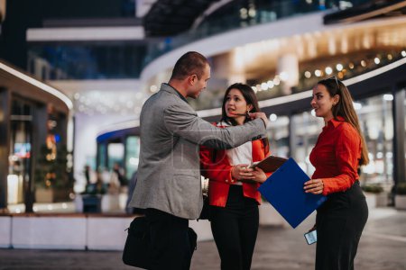 Three young corporate business partners engaged in a discussion about a project in a modern urban environment, showcasing teamwork and collaboration.