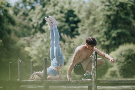 Two fitness enthusiasts practicing exercises on a wooden bridge in a natural setting, emphasizing outdoor workout and healthy lifestyle.