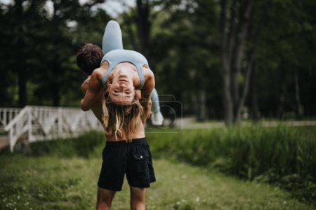 Man carrying his girlfriend playfully while walking in the park, enjoying a fun and carefree moment together.
