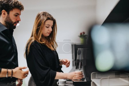 Two coworkers casually interact while making coffee in their office kitchen. A moment of relaxation and conversation during a workday.