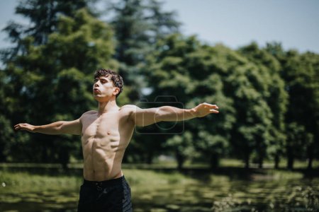 Jeune homme musclé effectuant de la calisthénique dans un parc extérieur pittoresque, les bras tendus pendant une routine d'échauffement