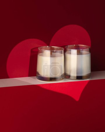 Photo for Candles against a spotlight in the shape of a heart on a red background - Royalty Free Image