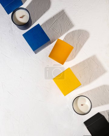 Foto de Velas de caja en diferentes colores sobre una superficie de textura blanca con sombras duras - Imagen libre de derechos
