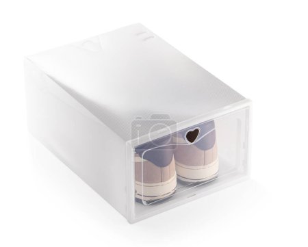 Praktische Schuhaufbewahrungsbox mit praktischer Klapptür, die ein Paar Turnschuhe zeigt, isoliert auf weißem Hintergrund. Funktionales Interieur-Zubehör für einfache Raumorganisation