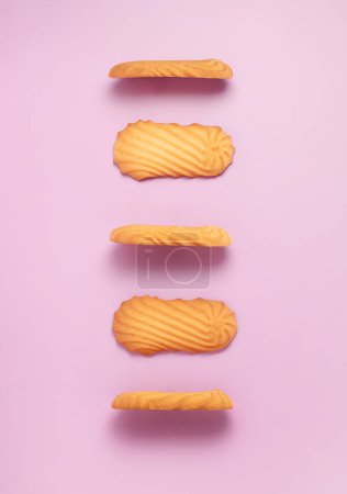 Foto de Galletas de mantequilla danesa doradas suaves y crujientes perfectamente alineadas con el fondo rosa. Presentación simple y elegante del popular dulce al horno - Imagen libre de derechos