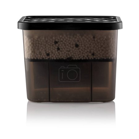 Moisture absorber half filled with hygroscopic granules visible through semi-transparent brown container, with vented black lid on top and clean label area for branding or product informatio