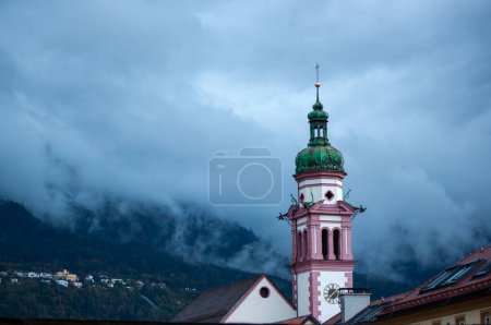 Foto de Austria, Tirol, Innsbruck, campanario de la iglesia Servitenkirche en el fondo de la montaña en las nubes - Imagen libre de derechos