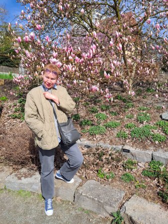 Femme mûre en pleine croissance près d'un magnolia en fleurs. Allemagne