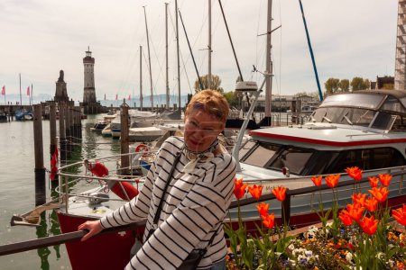Foto de Mujer madura atractiva cerca de un macizo de flores en el puerto de Lindau, Baviera - Imagen libre de derechos