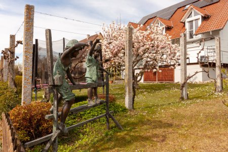 HAGNAU, GERMANY - MARCH 29, 2024: Bronze figures of children on the fence. Sculpture on the street in Hagnau