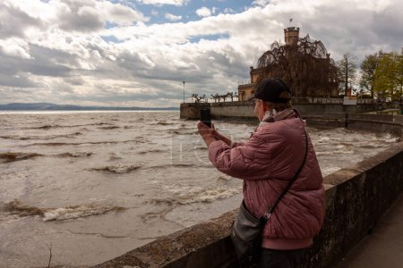 Reife Frauen fotografieren Wellen des Bodensees mit dem Smartphone. Deutschland, Langenargen