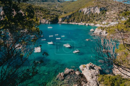 Blick auf den Strand von Rovinia mit klarem, blauem Meerwasser und festgemachten Booten. Erstaunlich azurblaue Natur Hintergrund. Private Küste auf der griechischen Insel Korfu, luxuriöses Reiseziel. Hochwertiges Foto
