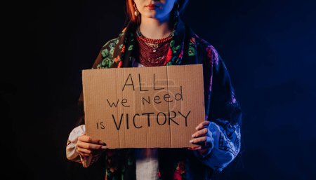 Foto de Ukrainian woman with cardboard All we need is victory. Ukraine win war. Protest, democracy, liberty, demonstration, russian aggresion concept. High quality photo - Imagen libre de derechos