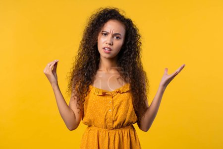 Photo for Irritated curly woman showing bla-bla-bla gesture with hands, rolling eyes on yellow background. Empty promises, blah concept. Lier. High quality photo - Royalty Free Image