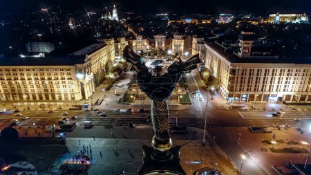 Téléchargez les photos : Kiev, Ukraine - Avril 2023 : Place Maidan Nezalezhnosti la nuit - vue aérienne sur les drones. Monument de l'Indépendance - Béréhynie dans le centre. Golden belle statue de femme ukrainienne. - en image libre de droit