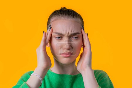 Photo for Portrait of beautiful suffering woman having headache, yellow studio portrait. Girl putting hands on head. Concept of migraine problems, medicine, illness, magnetic storms concept - Royalty Free Image