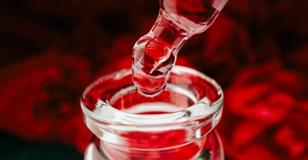 Photo for Acid peeling in bottle. Producing liquid aroma serum extract. Red vibrant concentrate drops dripping from pipette into glass container. Abstract skin care products. - Royalty Free Image