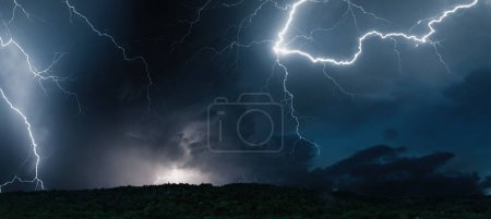 Nachtstürmischer Himmel über dem Wald. Schöne Blitze schlagen ein. Gewitterwolken. Natürliche elektrische Gefahr.