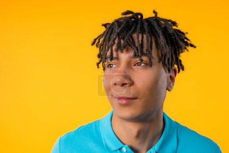 Foto de Amistoso joven afroamericano con dreadloocks sobre fondo de estudio amarillo. Copiar espacio. Estudiante adolescente. Foto de alta calidad - Imagen libre de derechos