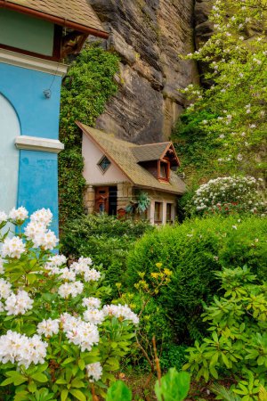 Téléchargez les photos : Fragment de maison construit dans la roche avec de belles fleurs. Hrensko, République tchèque - en image libre de droit