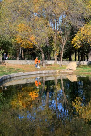 Photo for The photo was taken in the Ukrainian city of Odessa. The shooting location is an old public park called Dyukovsky Garden. In the picture, the artist paints a picture of a lake in which trees with autumn foliage are reflected. - Royalty Free Image