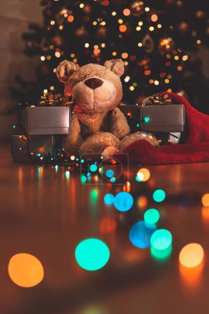 Foto de Hermoso interior de la casa festiva. Decoración de Nochebuena. Oso con regalos bajo hermoso árbol de Navidad decorado con luces de colores. Año Nuevo - Imagen libre de derechos
