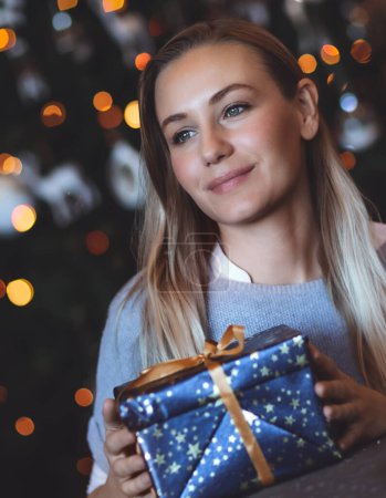 Téléchargez les photos : Portrait d'une fille rêveuse appréciant les cadeaux à la maison sur fond d'arbre de Noël décoré. Célébration des vacances d'hiver. Confortable réveillon de Noël. Bonne année - en image libre de droit