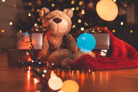 Téléchargez les photos : Ours mignon avec des boîtes-cadeaux en argent sous beau sapin de Noël lumineux. Bonne année. Veille de Noël magique à la maison. - en image libre de droit
