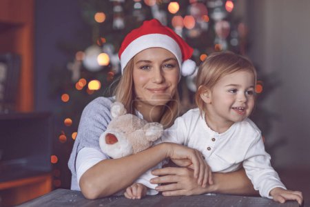 Foto de Mamá feliz con su bebé celebrando la Navidad en casa. Recibir regalos. Decoración del árbol de Navidad. Disfrutando de vacaciones de invierno en familia. - Imagen libre de derechos
