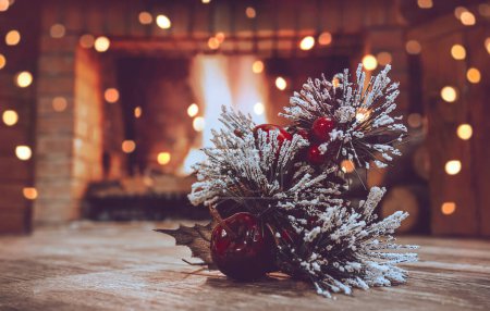 Photo for Christmas Still Life in Winter House Decorated with Festoon. Pine Tree Branch Decorated with Red Berries and White Snow Near Fireplace. Xmas Mood. - Royalty Free Image