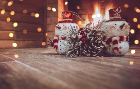 Photo for Christmas Home Decor. Winter House Decorated with Festoon. Two Little Snowman and Pine Tree Branch Near Fireplace. Photo with Copy Space. - Royalty Free Image